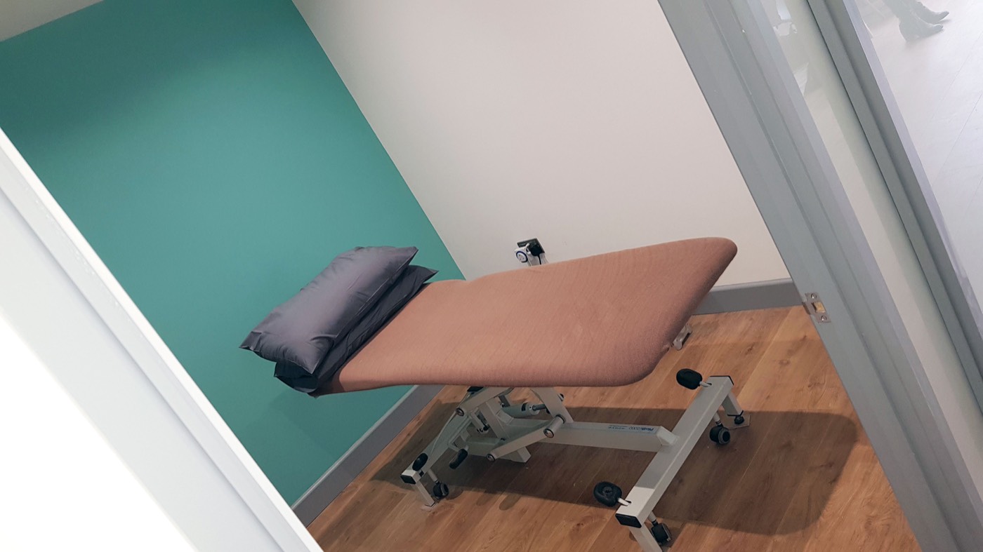 A treatment room with a couch against a teal wall