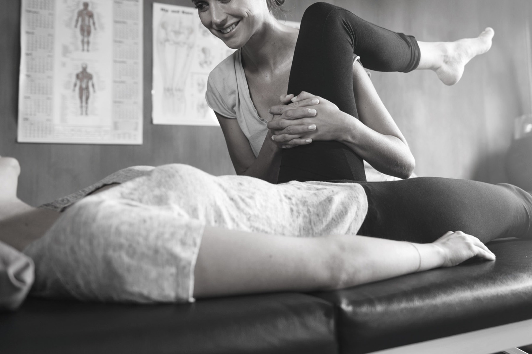 A physiotherapist working on a client's knee and hip on the treatment couch